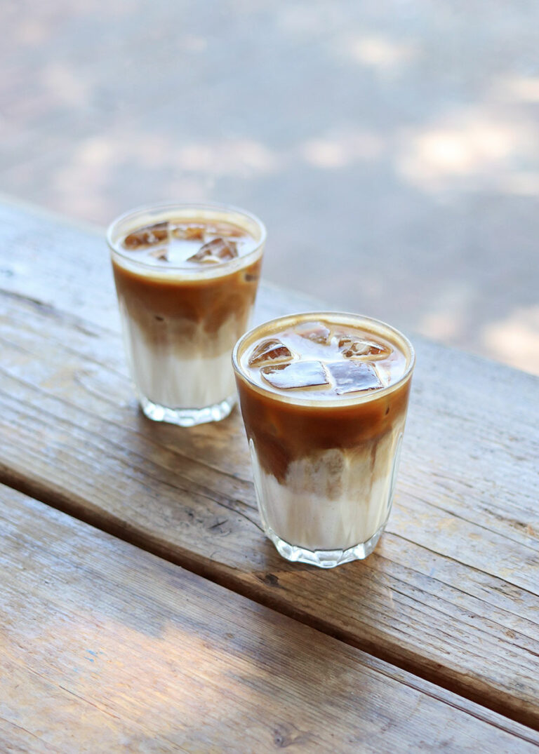 Zwei Gläser Iced Latte auf einem Holztresen